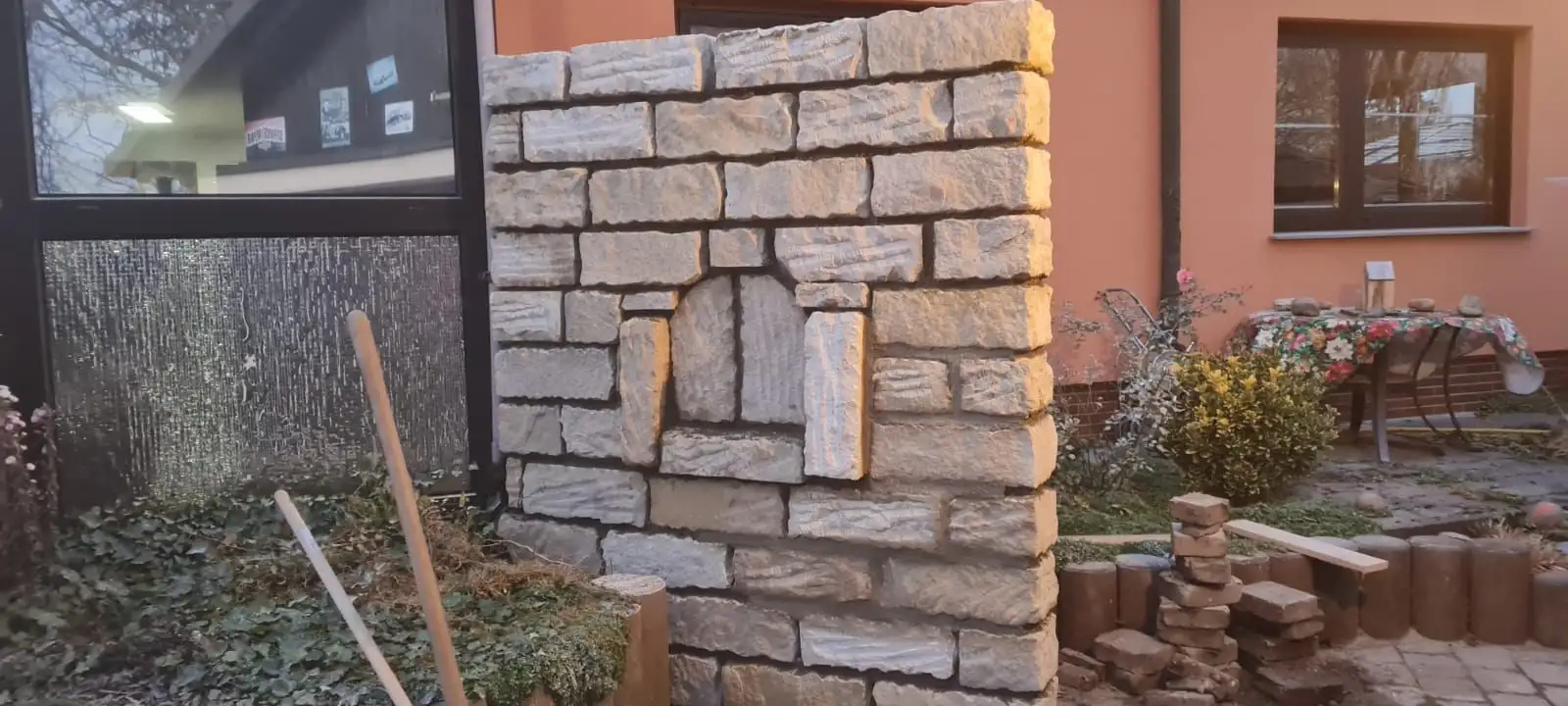 Natursteinsäule im Bau mit Nische, daneben Werkzeug