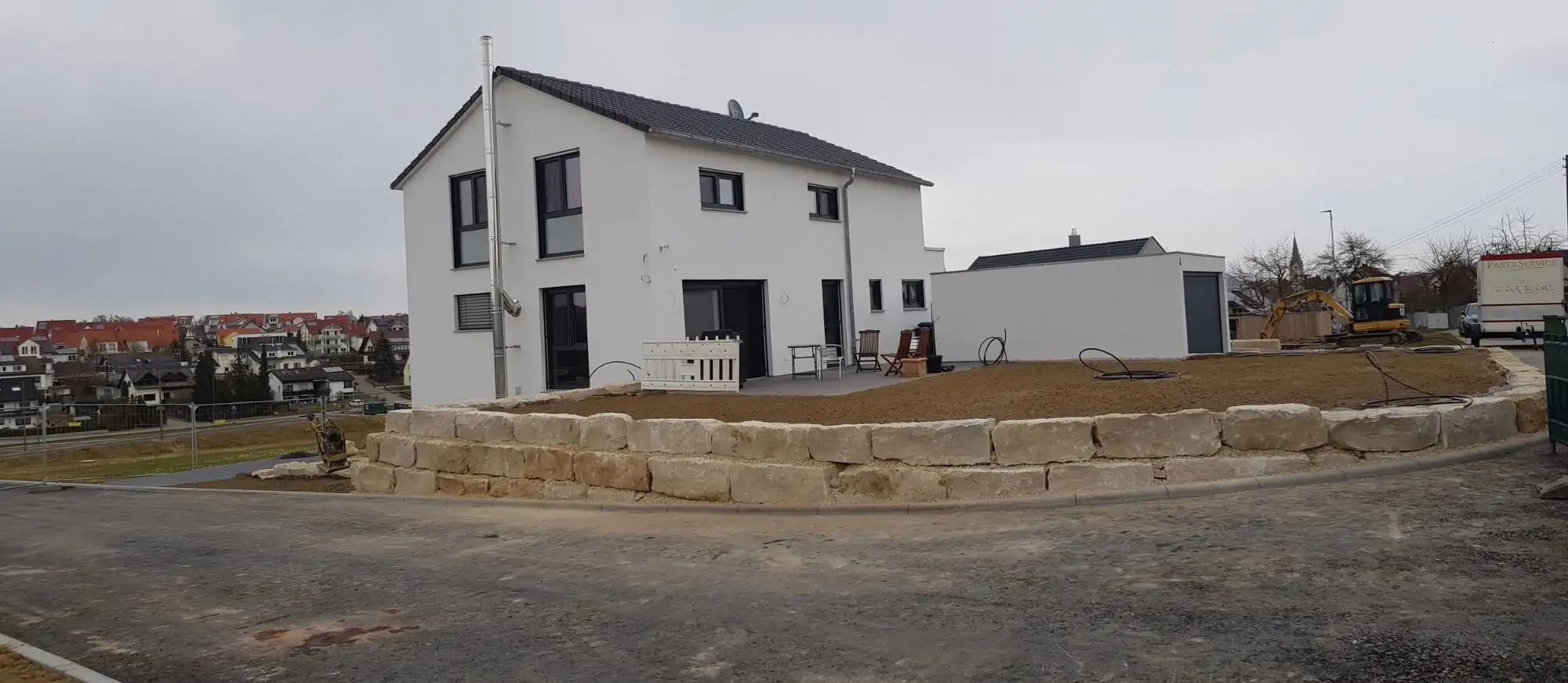 Neubau mit frisch gesetzter Kalksteinmauer, Gartenfläche noch im Rohzustand