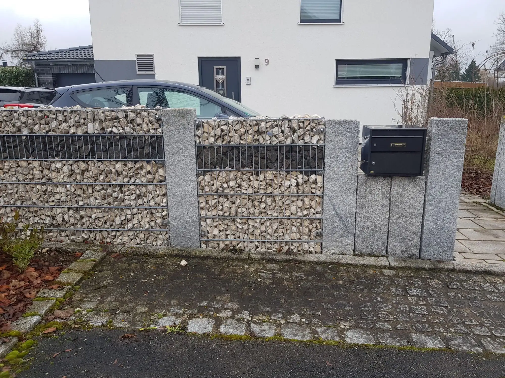 Vorgarten-Einfriedung aus Gabionen und Granitpfosten mit Briefkasten