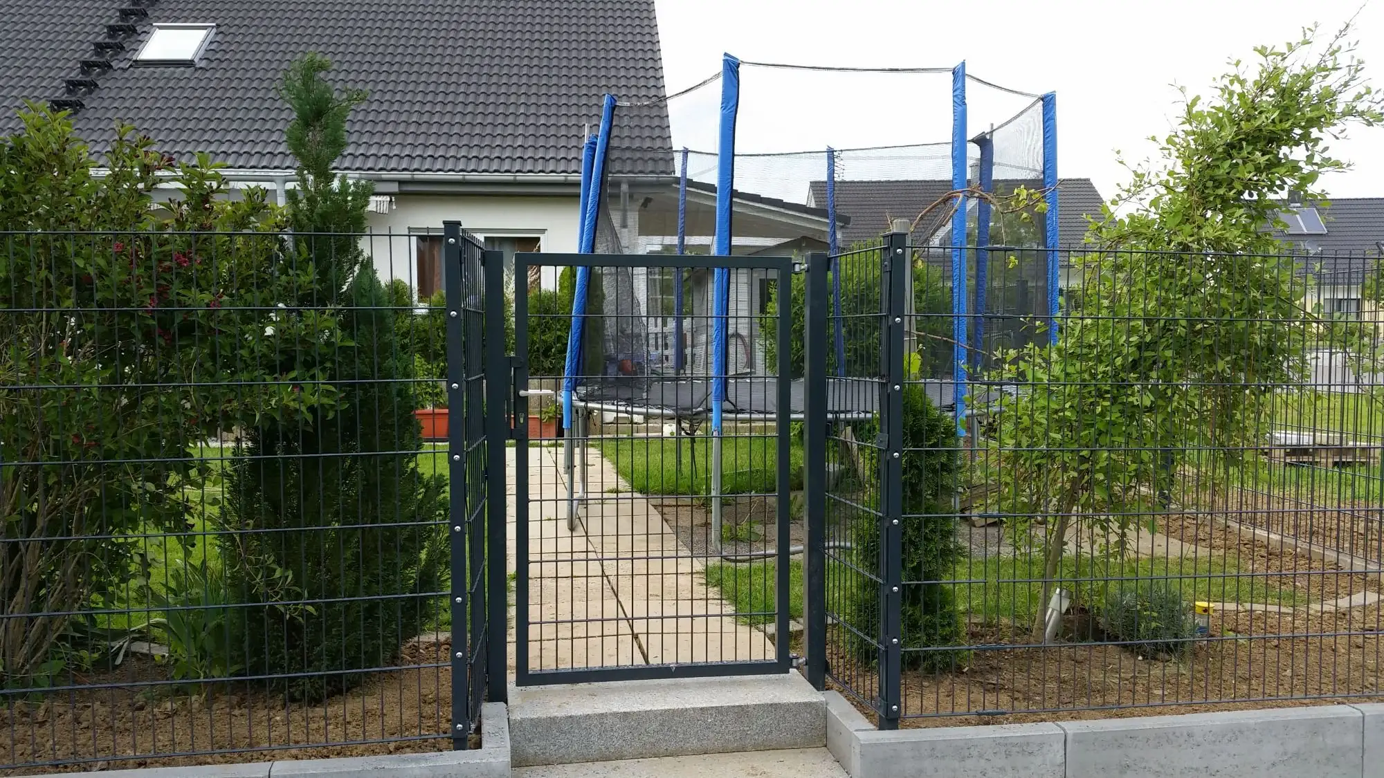 Doppelstabmattenzaun mit Gartentor vor einem Garten