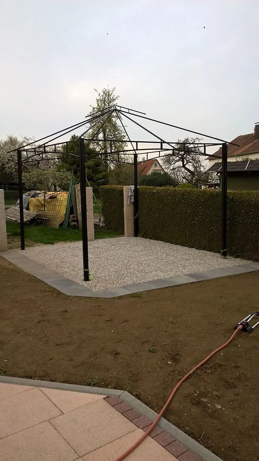 Metall-Pavillon auf einer Kiesfläche im Garten